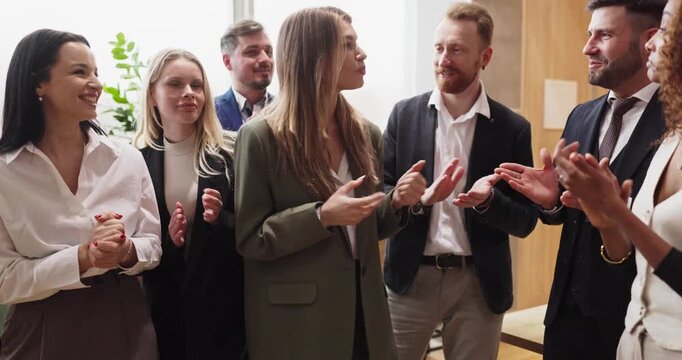 Team colleagues applause leader during business recognition meeting. Colleagues surround a teammate, smiling in celebration of milestone achievement. Concept of praise and shared success.