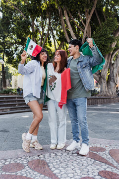 young Mexican people with flags to celebrate mexican independence day and cheering Viva Mexico 