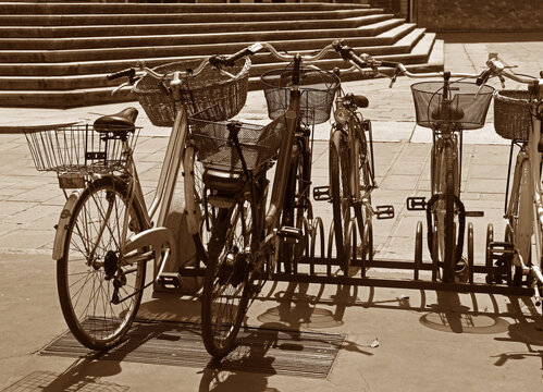 A group of bicycles parked in Piacenza's historic center near Piazza dei Cavalli. In the background, you can see the classic stone steps that characterize the historic buildings.