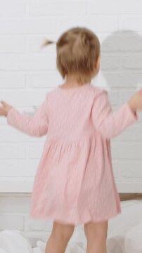 Cute little baby girl jumping on bed at home, happy childhood, energetic toddler.