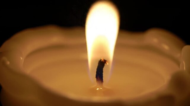 Close Up View of a Burning Candle Wick with Soft Glowing Flame at Night