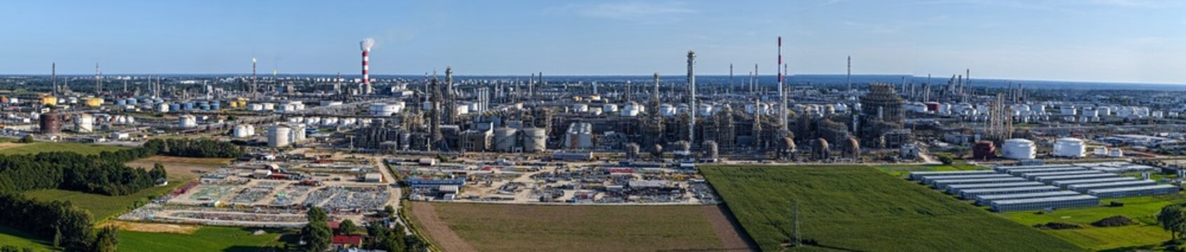 Aerial view of the PKN Orlen oil refinery with storage tanks, processing units, and tall chimneys, surrounded by agricultural fields in Plock, Masovian Voivodeship, Poland.