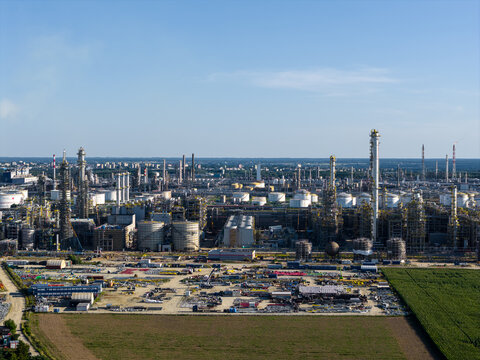 Aerial view of the PKN Orlen refinery complex with industrial towers, storage tanks, and infrastructure surrounded by agricultural fields in Plock, Masovian Voivodeship, Poland.