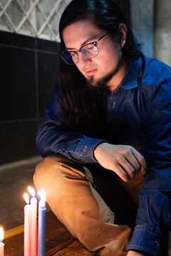 Young Man Kneeling Near Burning Candles. Candle Day, Colombia