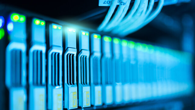 Close-up view of enterprise server rack showing active LED status indicators and high-density hard drive array in a modern data center environment with shallow depth of field