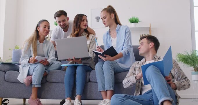 Group of happy students in casual clothes preparing an assignment in the living room. Young team working from home. Concept collaboration meeting, employee engagement, business meeting