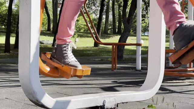 Person exercising on outdoor stepper fitness equipment in public park, performing stepping motion during outdoor workout, active lifestyle, fitness, recreation, healthy living