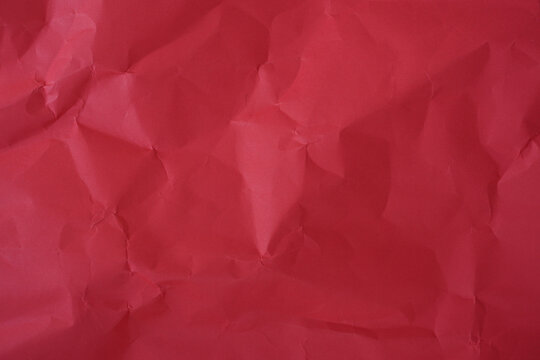 Crumpled red paper texture background with deep wrinkles, folds, and subtle shadows