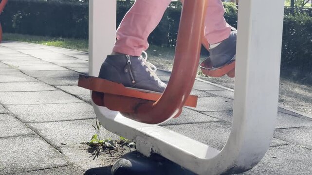 Person exercising on outdoor stepper fitness equipment in public park, performing stepping motion during outdoor workout, active lifestyle, fitness, recreation, healthy living