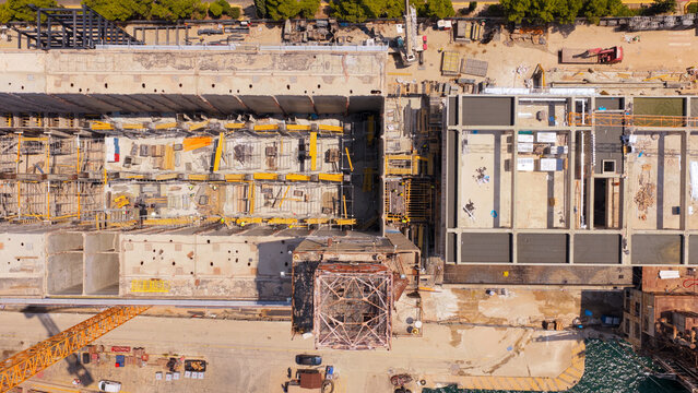 Aerial view of the construction site at Piraeus Harbour featuring concrete structures, scaffolding, and industrial machinery in the port area of Athens, Greece.
