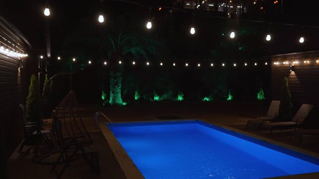 Luxurious private swimming pool glowing with vibrant blue lights in a tranquil backyard setting at night, with warm string lights creating a cozy and inviting atmosphere for relaxation or a party