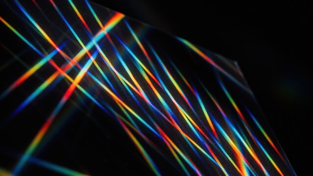 Colorful light lines creating abstract cross patterns against a dark background, representing spectral dispersion.