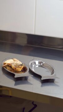 Chef placing freshly fried fish pieces onto fish-shaped metal plates using tongs, slow motion