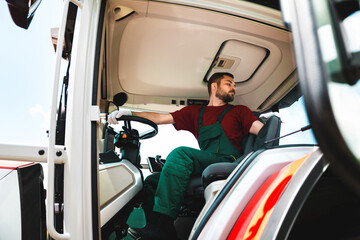 Naklejka premium Adult man wearing workwear operating a tractor.