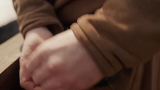 Close-up of hands securing leather pouch with buckle and flap, showing careful grip, pressing movement, and precise placement in rustic warm light for handmade storage, craft, or product use