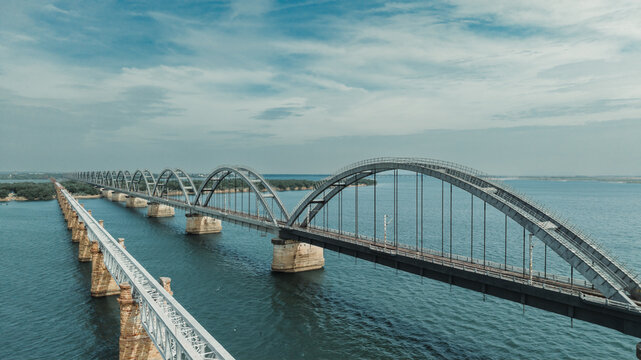 Aerial view of the Godavari Arch Bridge spanning the wide Godavari River with its distinctive steel arches and stone piers under a clear blue sky in Rajamahendravaram, Andhra Pradesh, India.