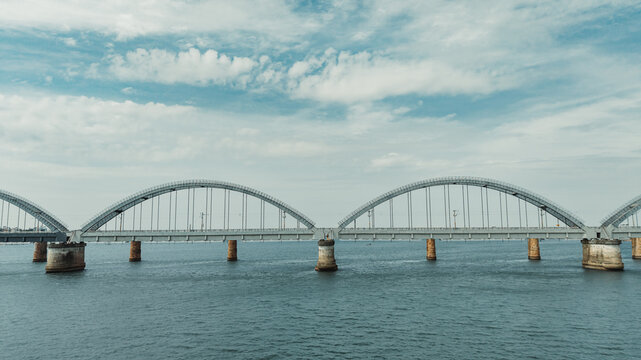 Aerial view of the Godavari Arch Bridge spanning the river with its distinctive steel arches under a cloudy sky in Rajamahendravaram, Andhra Pradesh, India.