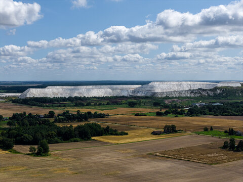 Aerial view of the industrial site and large white material piles of UAB IMLITEX surrounded by agricultural fields and forests in Kedainiai, Kauno apskritis, Lithuania.