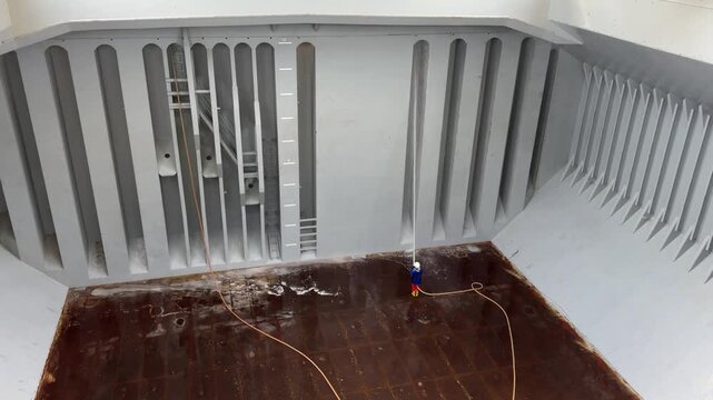 seafarer washing bukhead inside ship cargo hold.