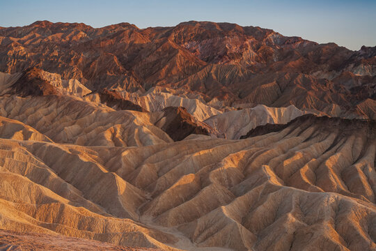 Beautiful scenic view of texture badlands hills and Amargosa mountains at golden sunrise