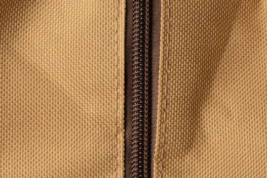 Zipper on a tan fabric bag with detailed stitching