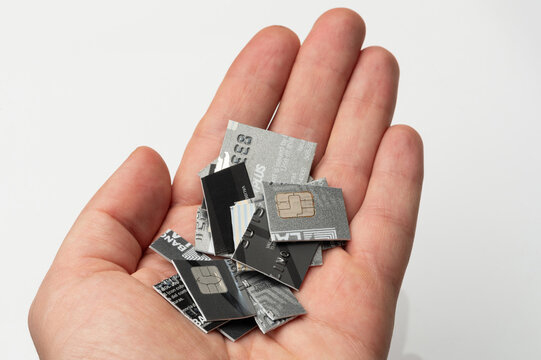 Hand holding pieces of cut credit cards on a plain background