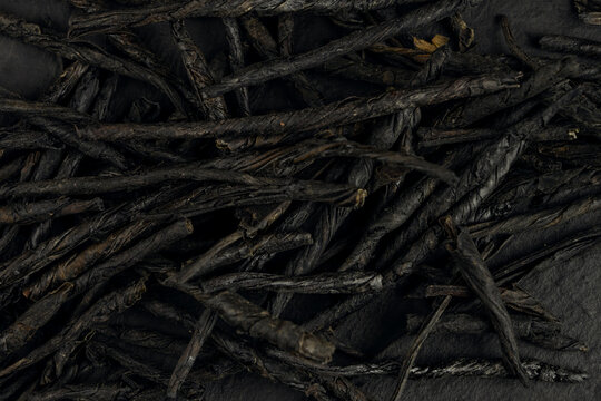 Kuding spear tea leaves arranged on a black background display their unique texture and shape