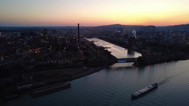 Cargo ship on the Danube in Linz (Austria) with steelworks and molten steel at dusk