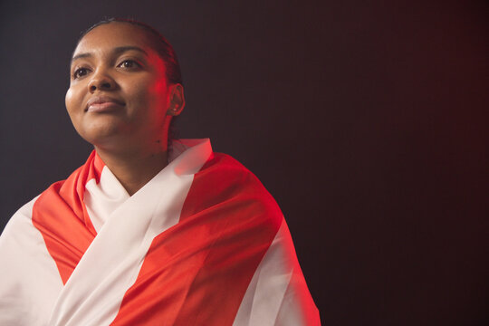 African American woman posing in studio, gazing upward, wearing red white draped cloth, copy space
