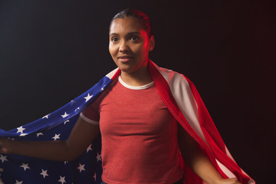 African American woman posing in studio, draping American flag, wearing red crewneck tee
