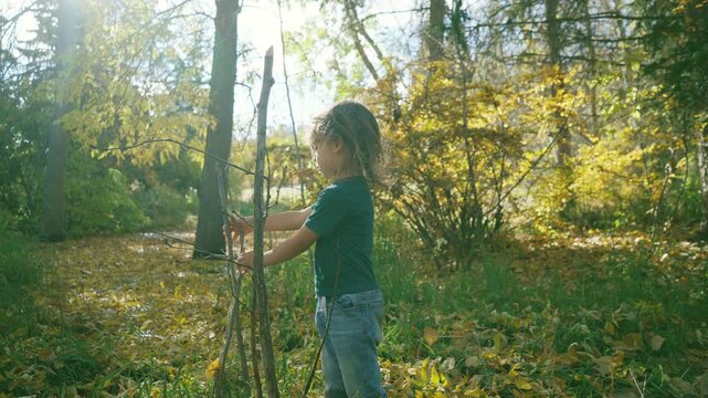 Young boy touching a thin sapling in autumn woods then reaching toward camera laughing
