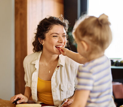 Portrait of a mother and daughter preparing and eating breakfast and having fun in the kitchen at home