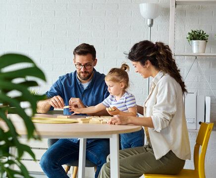Portrait of a happy amily at home, having fun playing wooden brick challenge game, playing board game jenga at home