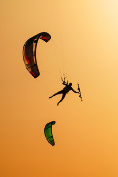 Kiteboarder suspended in the air against a glowing orange sky