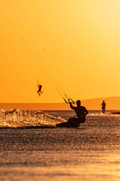 Kiter riding on sea water with warm golden sunset light