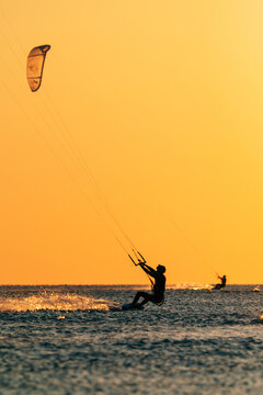Kiter riding over the sea with a kite in golden light