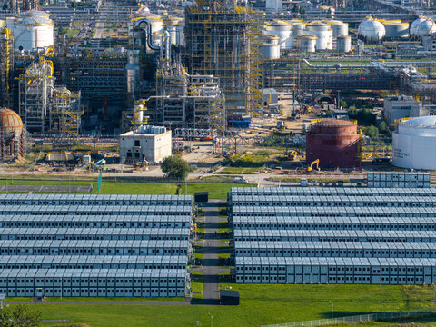 Aerial view of the PKN Orlen refinery complex, featuring industrial processing units, storage tanks, and rows of modular temporary housing in Plock, Masovian Voivodeship, Poland.