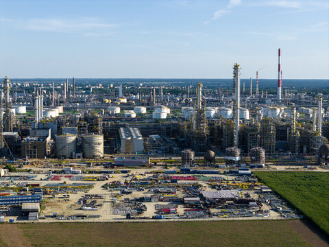 Aerial view of the PKN Orlen oil refinery complex featuring tall chimneys, storage tanks, and industrial infrastructure in Plock, Masovian Voivodeship, Poland.