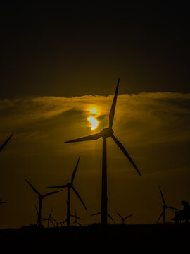 Aerial view of wind turbines silhouetted against a partial solar eclipse in the evening sky near the Volkswagenwerk Emden, Emden, Niedersachsen, Germany.