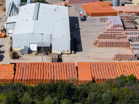 Aerial view of ZE PAK SA Elektrownia Patnow industrial facility featuring large storage areas with stacks of orange bricks and a warehouse building in Konin, Wielkopolskie, Poland.