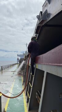 crew washing coaming of ship cargo hold.