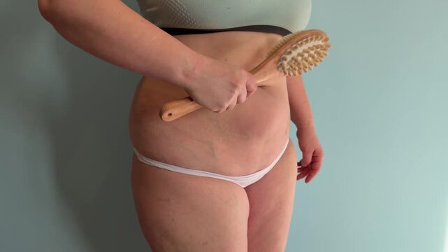 Side view of an overweight female massaging her stomach skin for lymphatic drainage close up