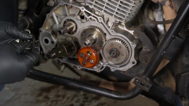 Mechanic repairing open motorcycle engine with gears