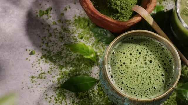 Hand whisking vibrant green matcha tea with traditional bamboo whisk, surrounded by matcha powder and tea-making ingredients. Illuminated by natural sunlight, creating an authentic tea ceremony scene