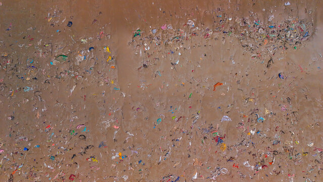 Aerial view of plastic waste and debris scattered across the sandy beach, highlighting environmental pollution in Indonesia.