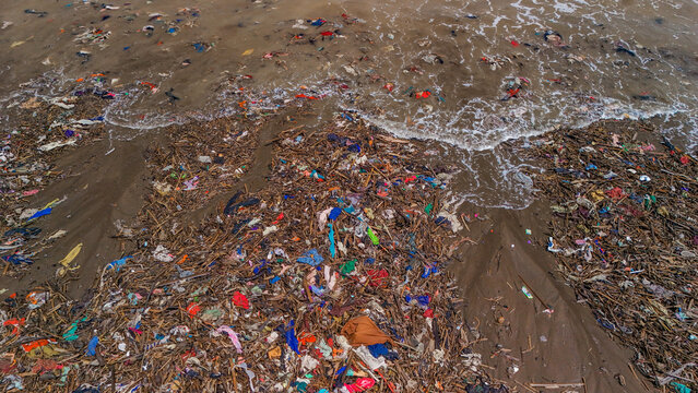 Aerial view of plastic waste and debris scattered across the sandy beach, highlighting the environmental pollution problem in Indonesia.