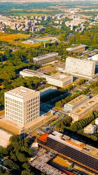 Vertical video. Rome, Italy. Palazzo della Civilta Italiana, the Square Colosseum with its grid of 216 travertine arches, aerial panoramic view over the EUR district under clear summer sky. Drone foo