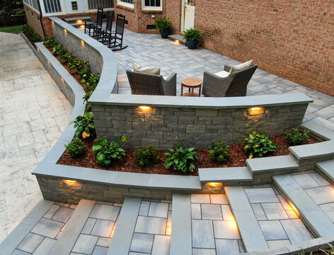 Elevated Wide Angle View Of Custom Stone Patio Retaining Wall And Tiered Stairs With Integrated Lighting