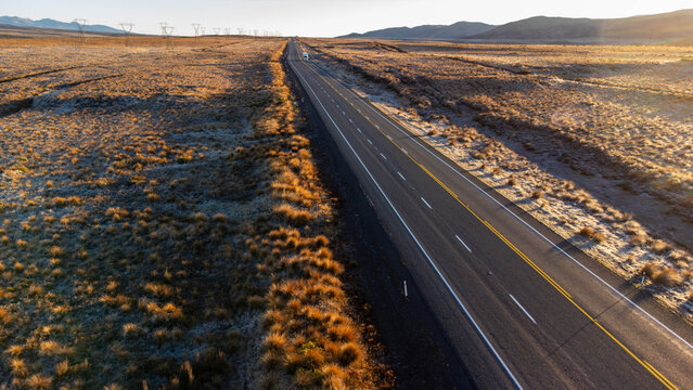Aerial view of Rangipo Desert with a long asphalt road stretching through the arid landscape under golden hour light in Waiouru, Manawatu-Whanganui, New Zealand.