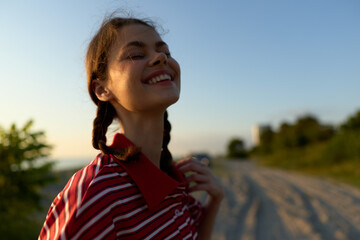 Naklejka premium A happy young woman with braids enjoying sunset outdoors. Lifestyle portrait of a smiling female expresses freedom, joy, and peace in a natural summer environment.